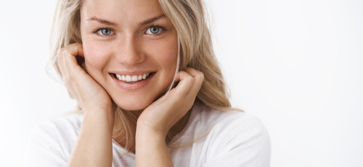 Headshot of attractive adult blond woman with tattoo leaning fac